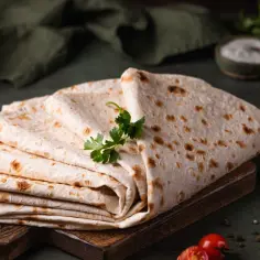 Stos cienkiego, puszystego lawaszu, idealnego do wrapów. Obok pomidorki, papryczka chili i przyprawy. Pyszny lawasz przepis na szybki posiłek.