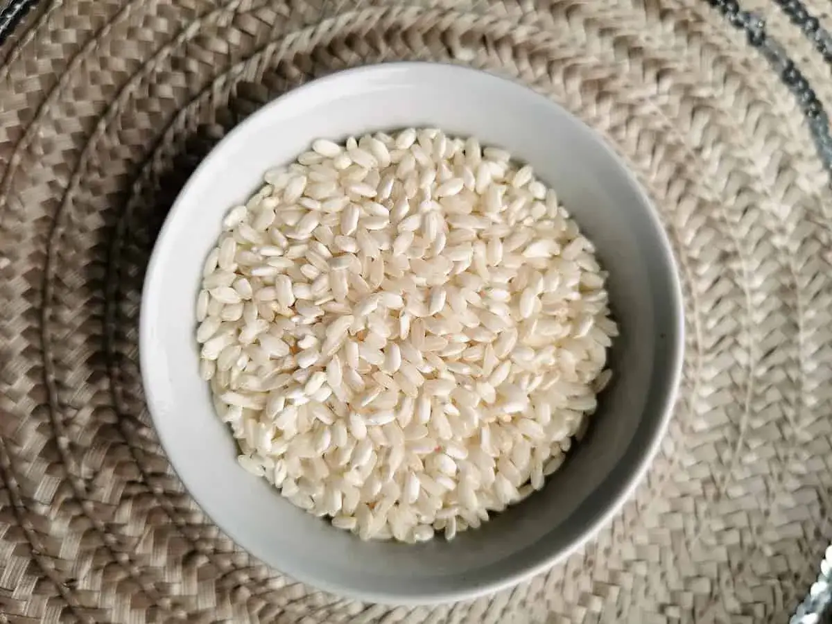 Biały ryż w miseczce, idealny do przygotowania kremowego risotto. Wybór odpowiedniego ryżu to klucz do sukcesu.